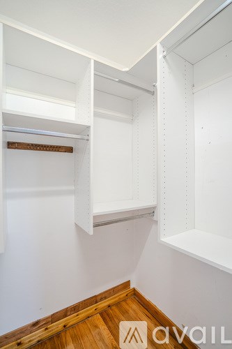 A white wall with a wooden floor and a white shelf.