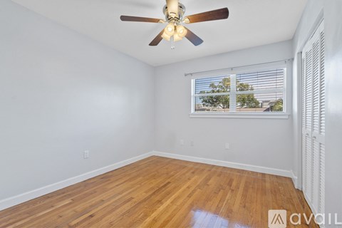 A room with a ceiling fan and wooden flooring.