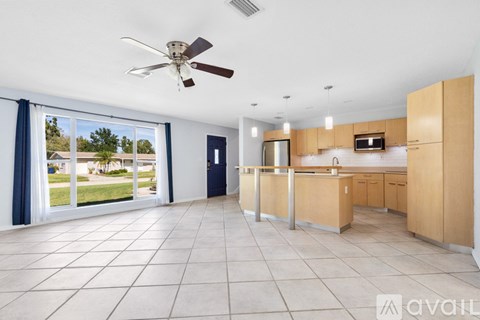 A spacious kitchen with a fan and a view of the outdoors through the sliding glass doors.