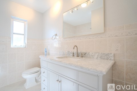 A bathroom with a white toilet, sink, and cabinets.