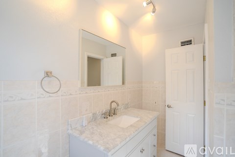A bathroom with a sink, mirror, and white cabinet.