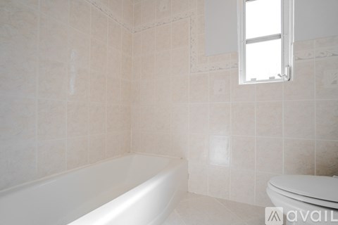 A white bathtub sits in a bathroom with beige tiles.