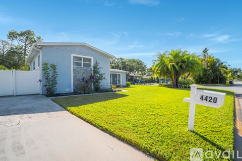 A white house with a number 4420 on a sign in front of it.