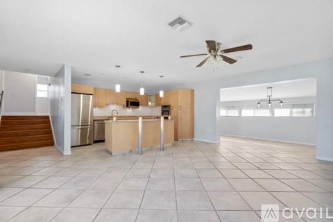 A spacious kitchen with a ceiling fan and tiled flooring.