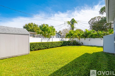 A backyard with a well-maintained lawn and a white fence.