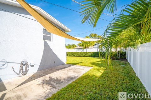 A white house with a palm tree in front.