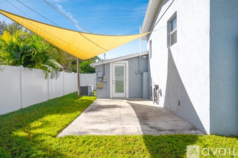A white house with a yellow shade over the walkway.