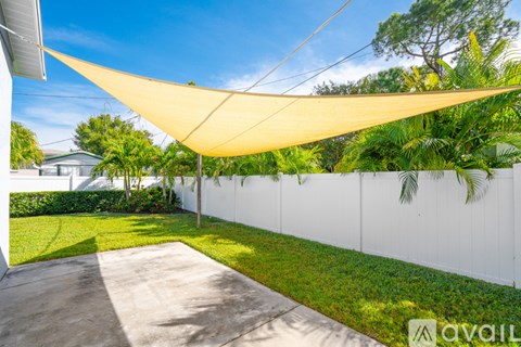 A patio area with a white wall and a yellow shade sail.