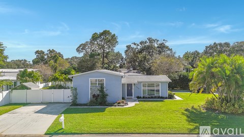 A house with a white fence and a green lawn is for sale.