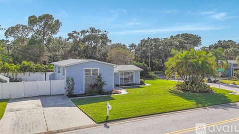 A house with a white fence and a green lawn is for sale.