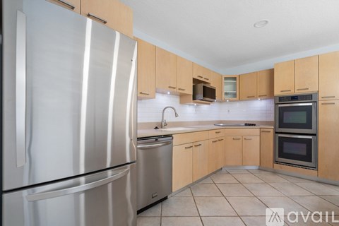 A kitchen with a stainless steel refrigerator and wooden cabinets.