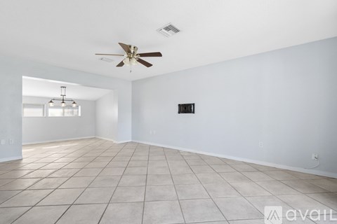 A spacious room with a ceiling fan and tiled flooring.