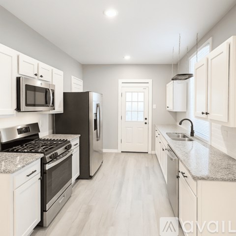 A kitchen with white cabinets and a black refrigerator.