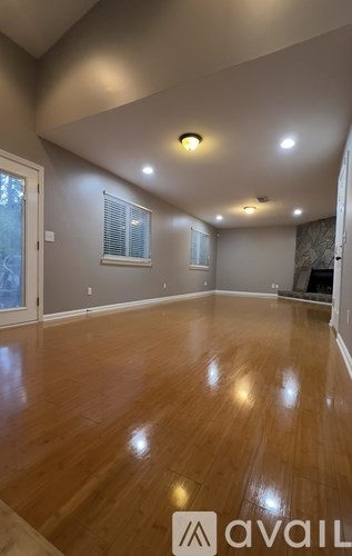 A spacious room with wooden flooring and recessed lighting.
