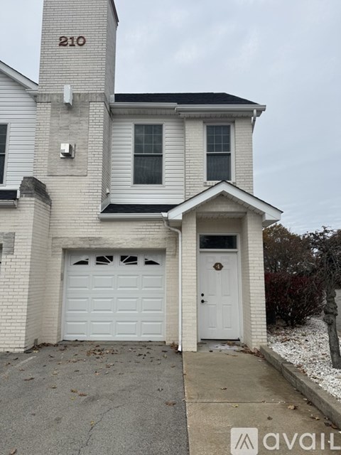 A two-story house with a white garage door and a number 210 on the top of the garage door.