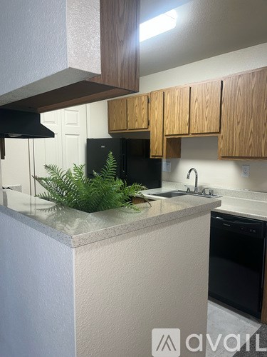 A kitchen with wooden cabinets and a black fridge.