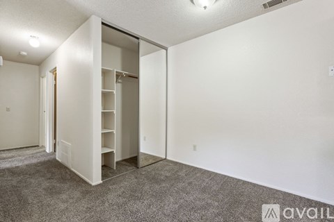 A room with a white wall and a grey carpet.