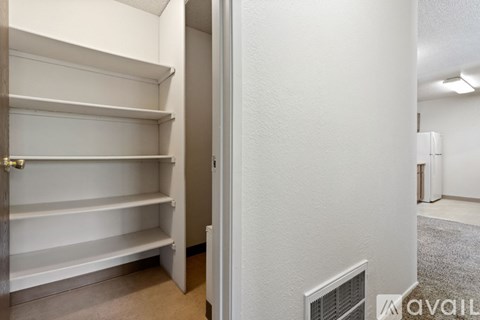 A white closet with shelves and a door leading to a hallway.