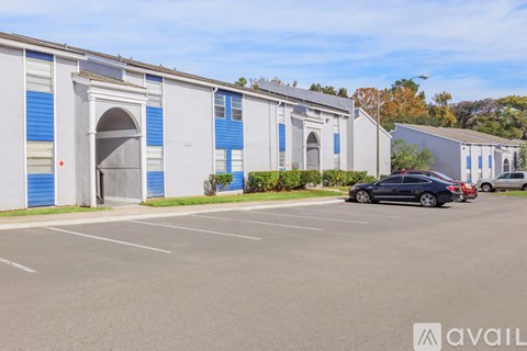 A parking lot with a building and cars parked in front.