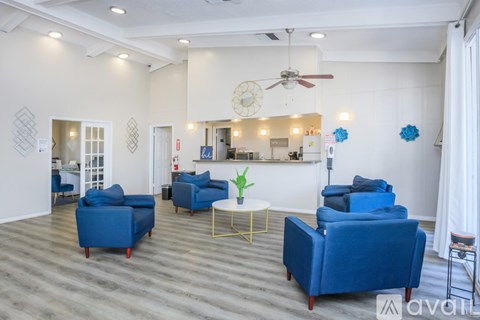 A living room with blue chairs and a fan.