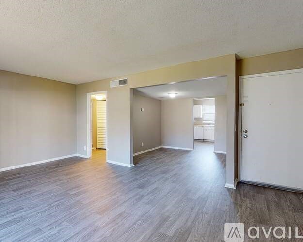 A spacious room with wooden flooring and white walls.
