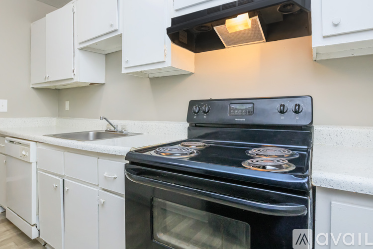 A black stove top oven with four burners and a glass door is in a kitchen with white cabinets.