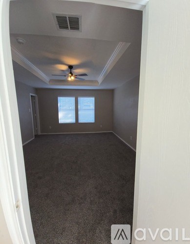 A room with a ceiling fan and carpeted floor.