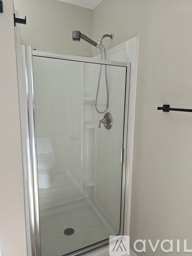 A shower stall with a glass door and a silver handle.