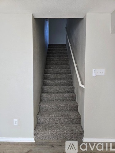 A staircase with a carpeted runner and white walls.