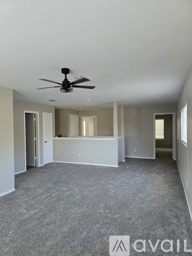 A spacious room with a ceiling fan and carpeted floor.