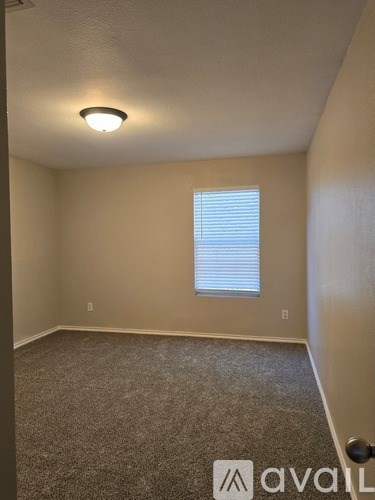 A room with a carpeted floor and a window with blinds.