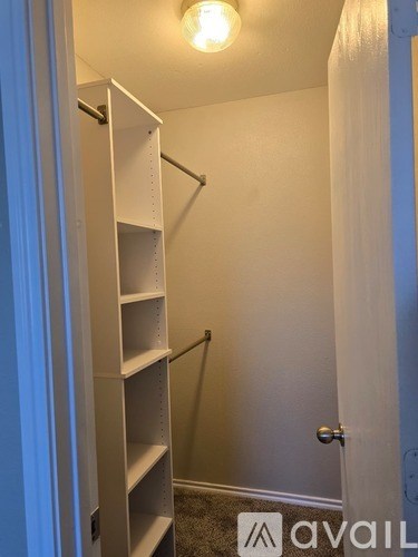 A white shelving unit in a room with a door.