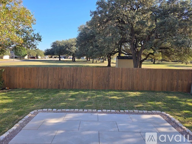 A backyard with a wooden fence and a stone patio.
