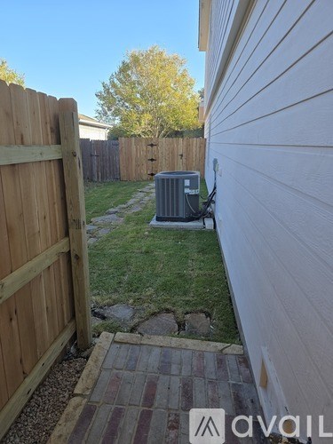 A wooden fence and a brick pathway lead to a house.
