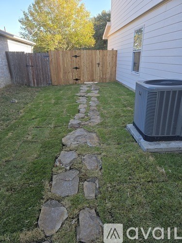 A backyard with a stone pathway leading to a house.