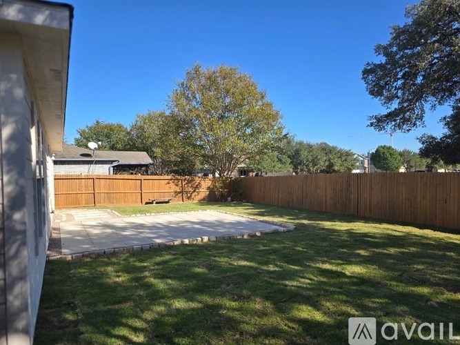 A backyard with a wooden fence and a tree.