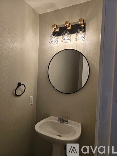 A bathroom with a white sink and a round mirror.