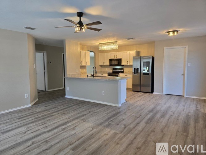 A spacious kitchen with a bar area and a ceiling fan.