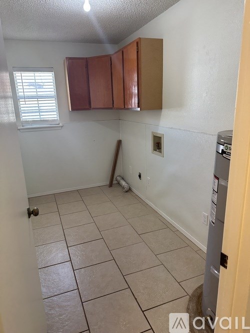 A room with a white wall and a window with blinds.