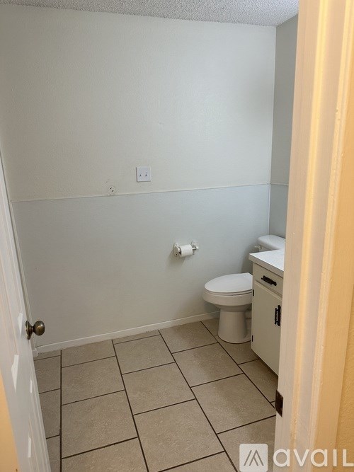 A bathroom with a toilet, sink, and tiled floor.