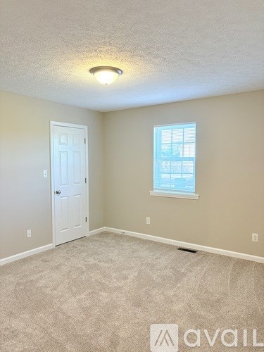 A room with a carpeted floor, a white door, and a window with blinds.