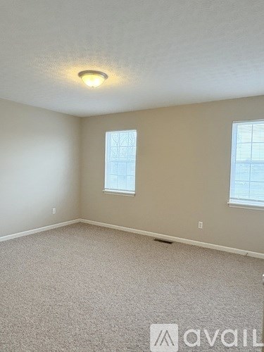 A room with a carpeted floor and a window with blinds.
