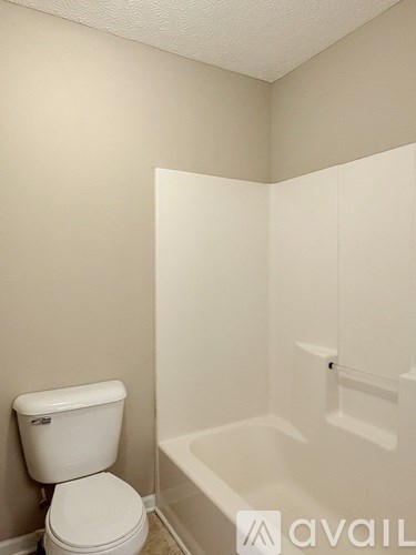 A white toilet sits next to a white bathtub in a bathroom.
