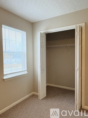 A room with a carpeted floor and a window with blinds.