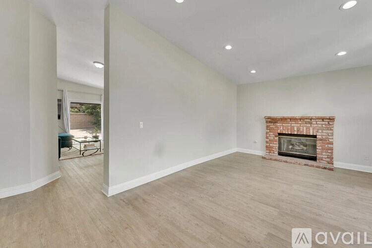 A spacious living room with a fireplace and wood flooring.