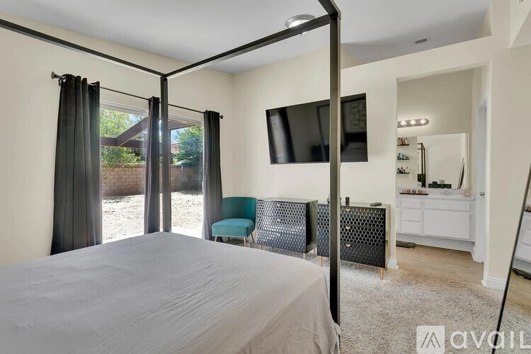 A bedroom with a bed, chair, and a television.