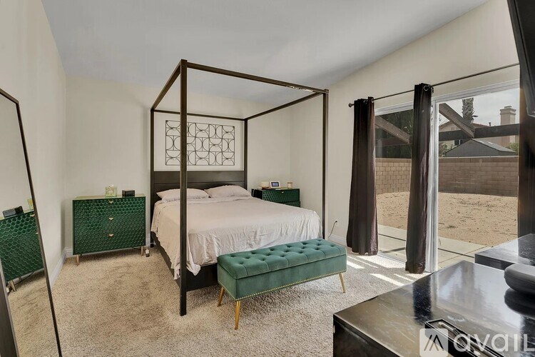 A bedroom with a four poster bed and a green footstool.