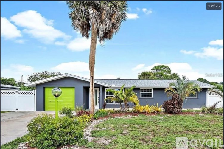 A house with a green door is surrounded by greenery.