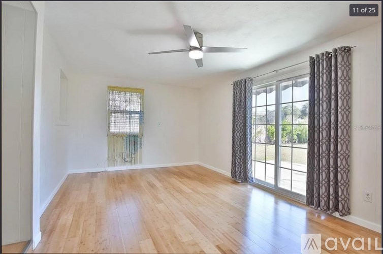 A room with a ceiling fan and a window with curtains.