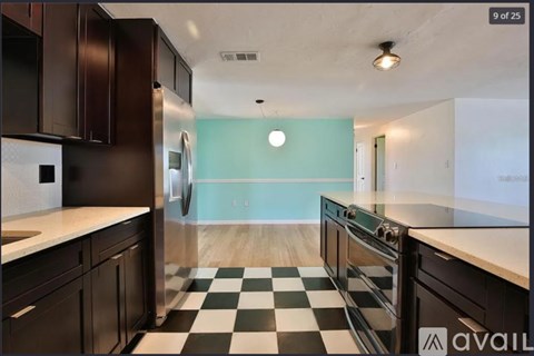 A kitchen with black cabinets and a checkered floor.